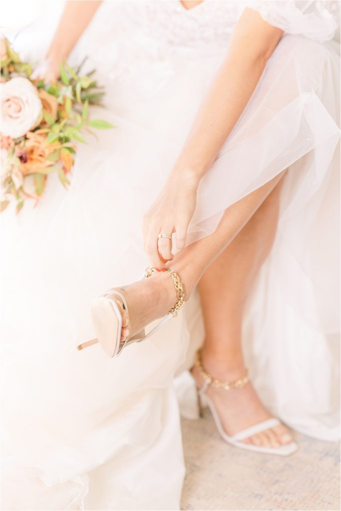 bride fastening high heel holding gorgeous bouquet Westwind Hills luxury wedding inspiration | Kelsey Alumbaugh Photography | #weddinginspiration #luxurywedding #stlouisweddingphotography #stlwedding #styledshootsacrossamerica