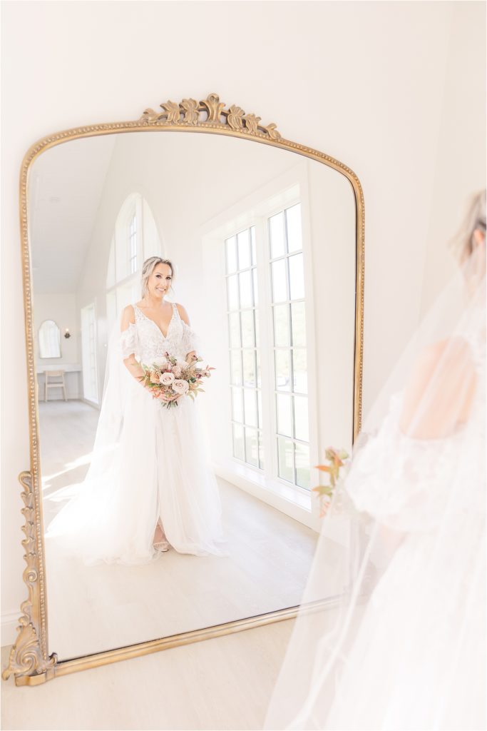 Bride looking into large gold frame mirror in getting ready suite at Westwind Hills Westwind Hills luxury wedding inspiration | Kelsey Alumbaugh Photography | #weddinginspiration #luxurywedding #stlouisweddingphotography #stlwedding #styledshootsacrossamerica