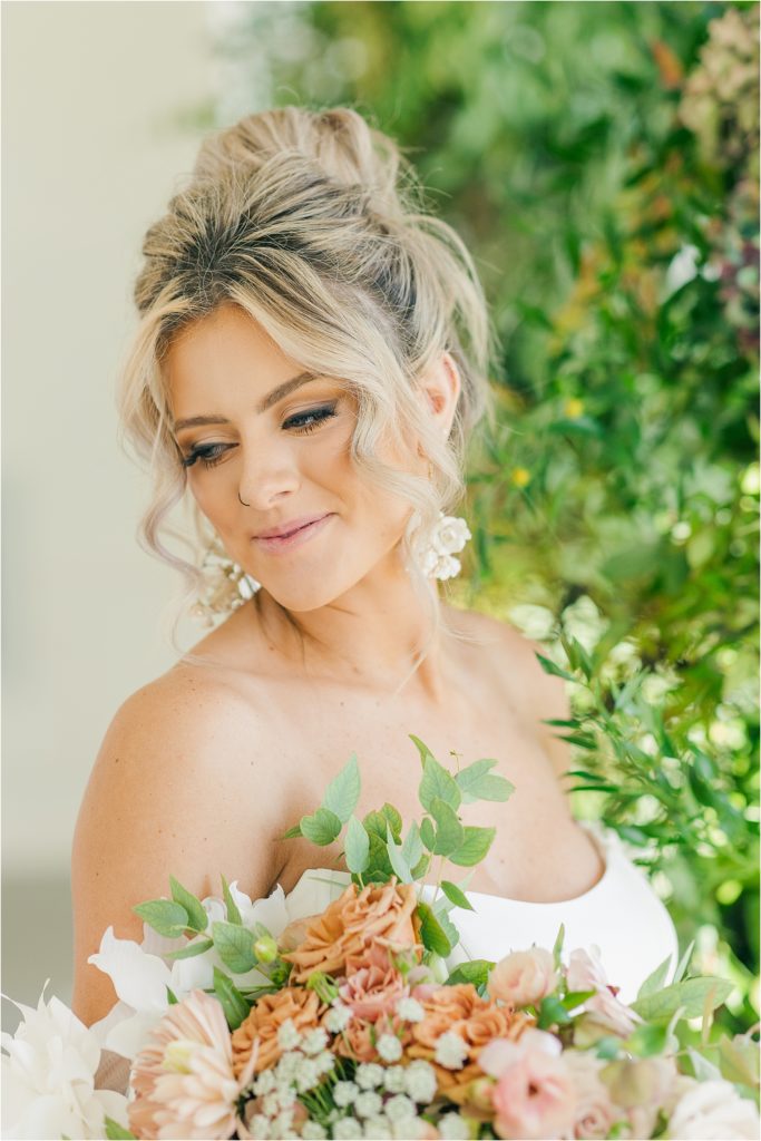 blonde bride in off the shoulder white gown with blush bouquet in front of greenery for wedding arch Westwind Hills luxury wedding inspiration | Kelsey Alumbaugh Photography | #weddinginspiration #luxurywedding #stlouisweddingphotography #stlwedding #styledshootsacrossamerica