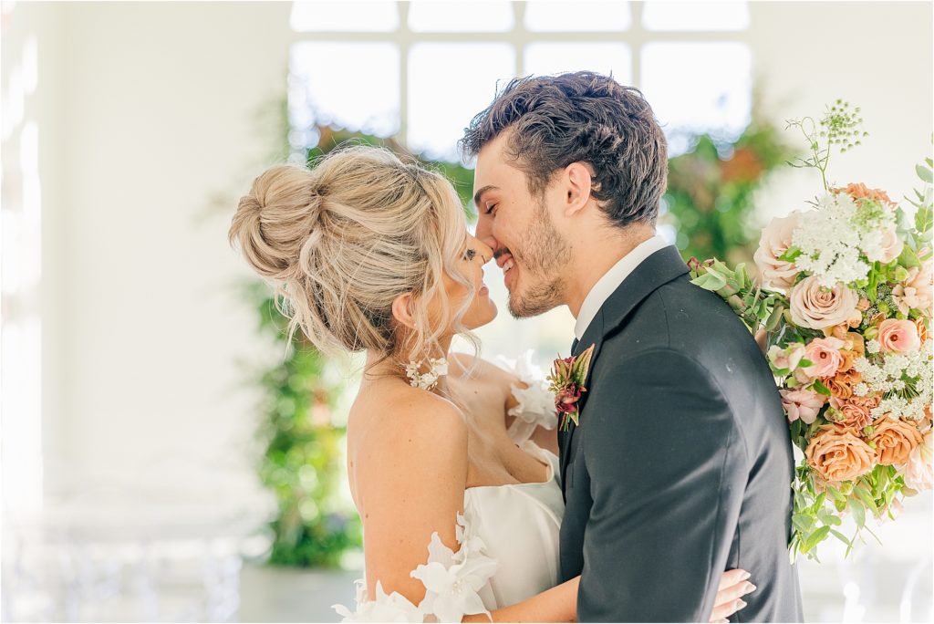 blonde bride in off the shoulder wedding gown smiling and about to kiss groom in black tux Westwind Hills luxury wedding inspiration | Kelsey Alumbaugh Photography | #weddinginspiration #luxurywedding #stlouisweddingphotography #stlwedding #styledshootsacrossamerica