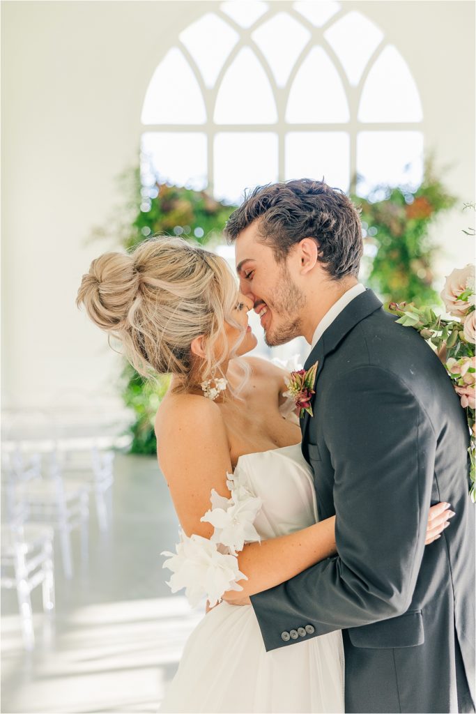 blonde bride in off the shoulder white gown about to kiss brunette groom in black tux Westwind Hills luxury wedding inspiration | Kelsey Alumbaugh Photography | #weddinginspiration #luxurywedding #stlouisweddingphotography #stlwedding #styledshootsacrossamerica