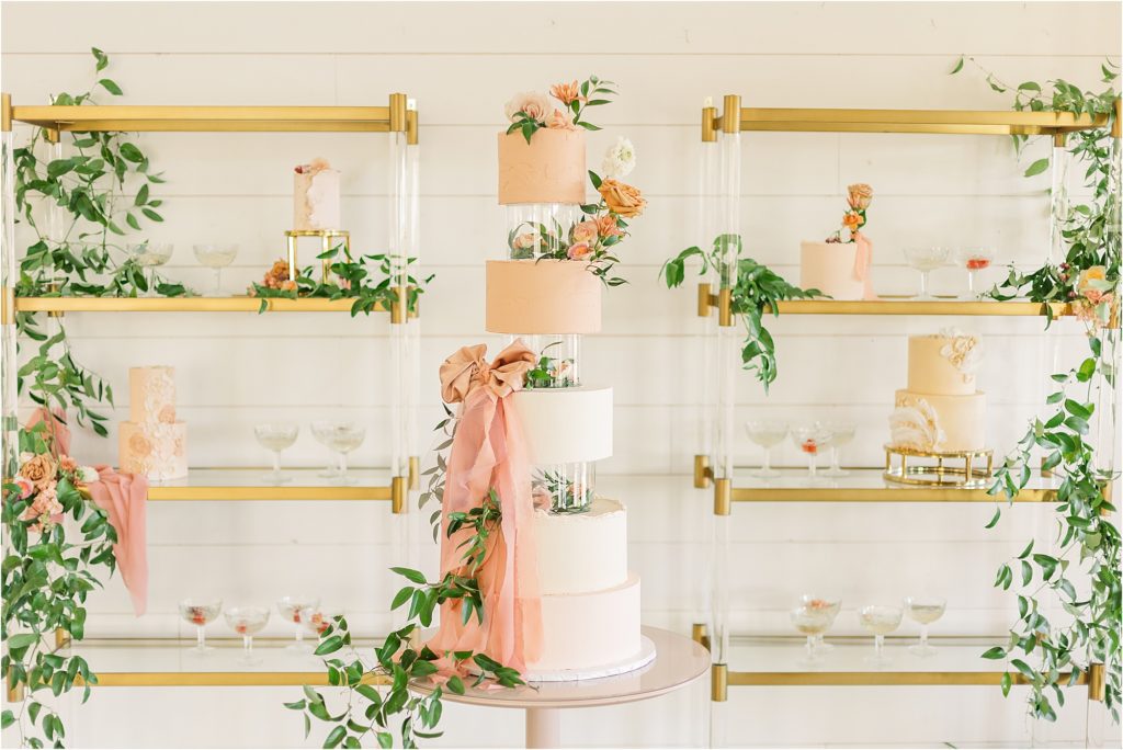 blush and white tiered wedding cake with satin ribbon with gold shelves of wedding desserts Westwind Hills luxury wedding inspiration | Kelsey Alumbaugh Photography | #weddinginspiration #luxurywedding #stlouisweddingphotography #stlwedding #styledshootsacrossamerica