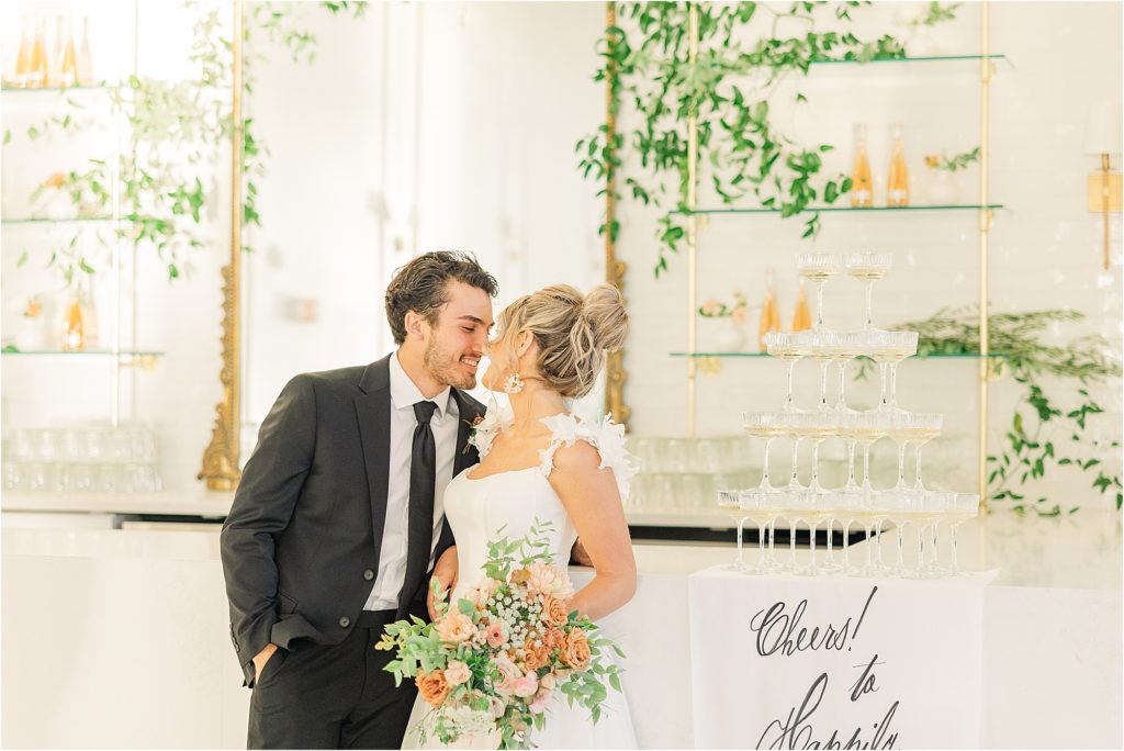 bride and groom kissing at westwind hills reception bar with champagne tower Westwind Hills luxury wedding inspiration | Kelsey Alumbaugh Photography | #weddinginspiration #luxurywedding #stlouisweddingphotography #stlwedding #styledshootsacrossamerica