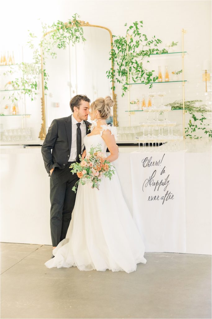bride and groom kissing at westwind hills reception bar with champagne tower Westwind Hills luxury wedding inspiration | Kelsey Alumbaugh Photography | #weddinginspiration #luxurywedding #stlouisweddingphotography #stlwedding #styledshootsacrossamerica