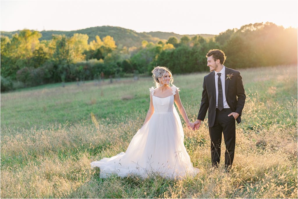 bride and groom in golden hour sunlight drench fall colored field at westwind hills outside st. louis mo additional wedding cake - tan with embellishments blush and white tiered wedding cake with satin ribbon with gold shelves of wedding desserts Westwind Hills luxury wedding inspiration | Kelsey Alumbaugh Photography | #weddinginspiration #luxurywedding #stlouisweddingphotography #stlwedding #styledshootsacrossamerica