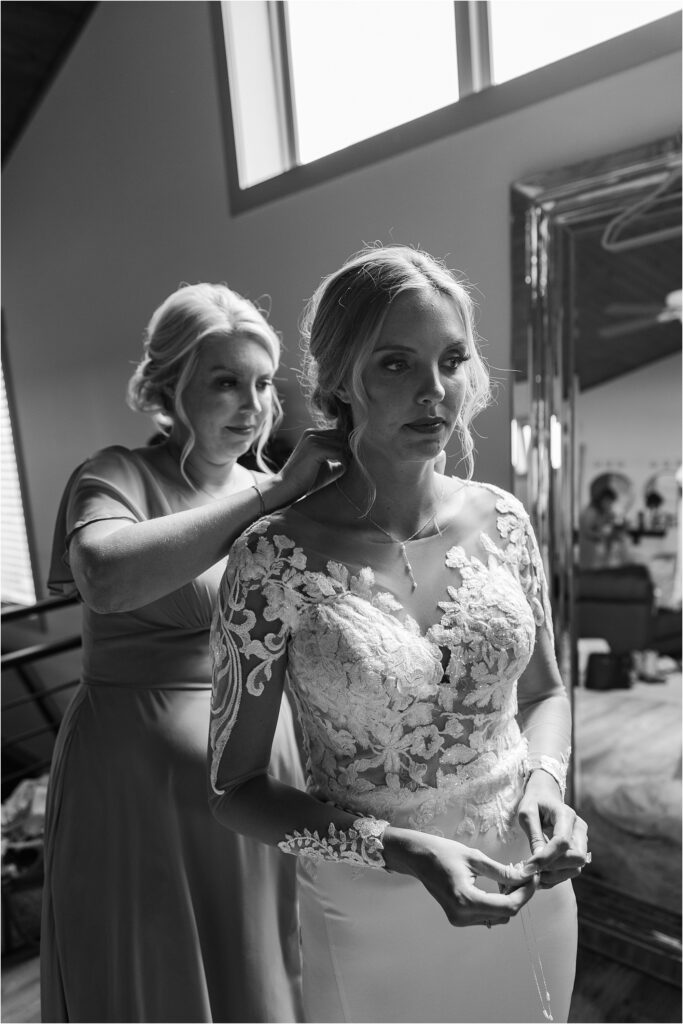 Maid of honor buttoning bridal gown - helping bride in bridal suite at Eagle Bluff Ranch, Waverly, Mo - Haylee + Blake | Missouri River spring wedding | Kansas City wedding photographer | Kelsey Alumbaugh Photogrpahy | #kansascitywedding #missouriweddingphotographer #missourispringwedding